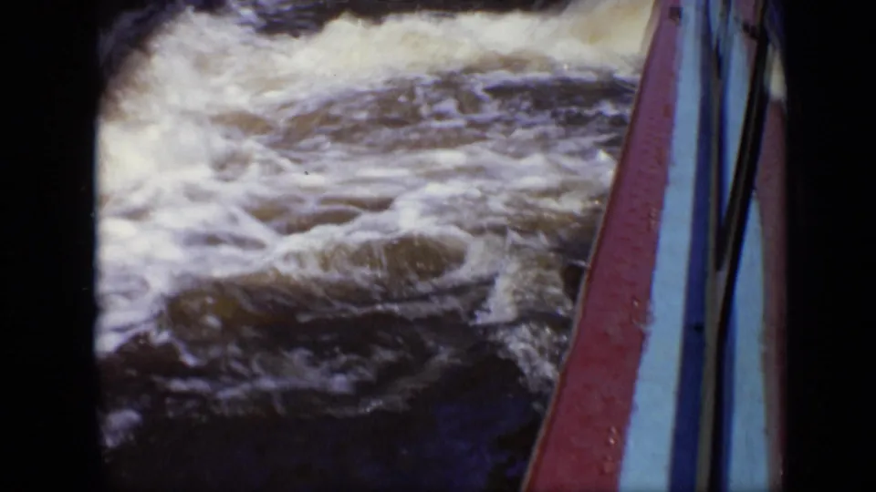 Foaming water churns beside a red and blue boat edge in this 1971 Moscow 8mm frame, emphasizing motion from a passenger viewpoint.
