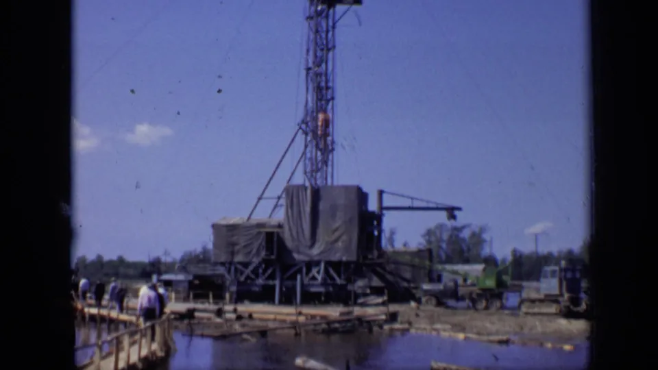 The camera frames the pier edge, visitors, dark water and tarped drilling structure in a Moscow 1971 home-movie view.