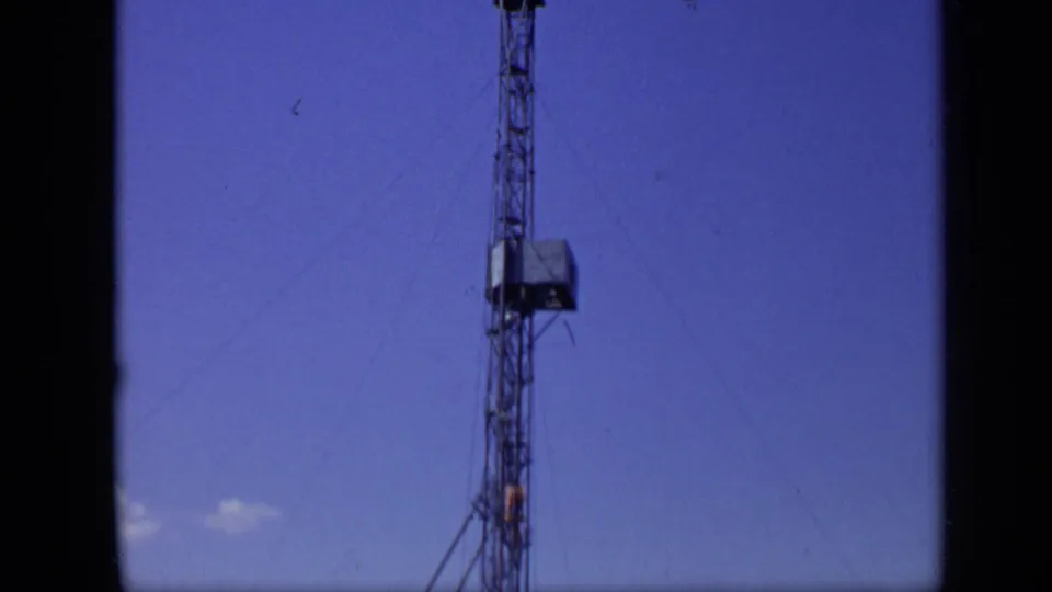 A tall tower stands against clear sky in the supplied 1971 Moscow river footage, with wires extending from the structure.