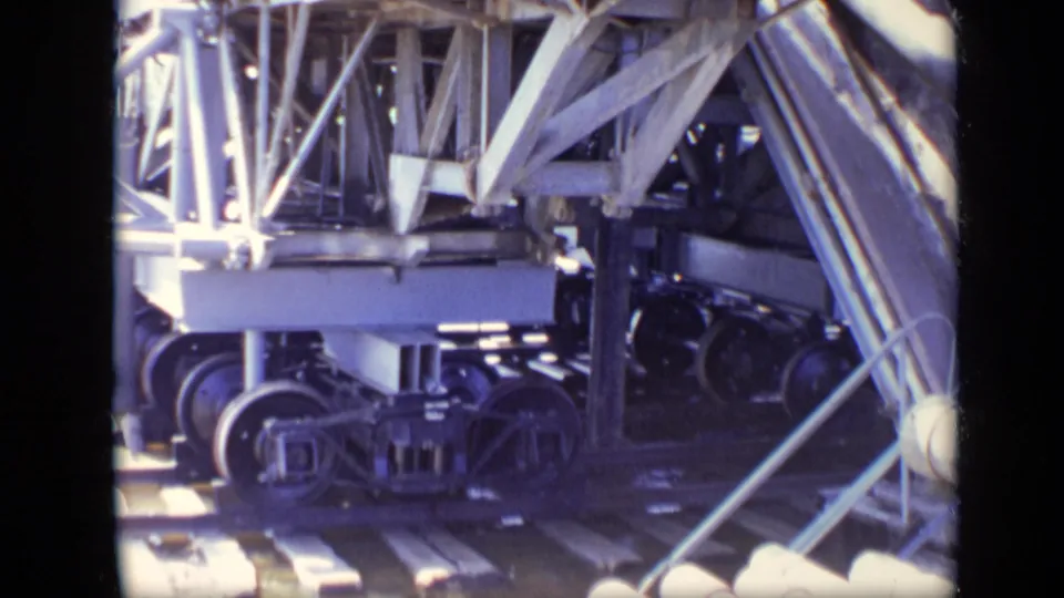A close industrial frame shows truss beams, wheel assemblies, rails, and structural supports likely connected to ferry dock equipment.