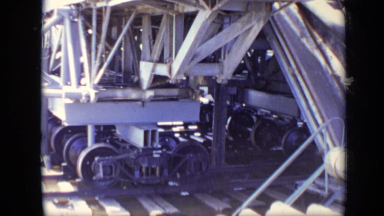 Close view of wheeled industrial machinery beneath a metal truss structure.