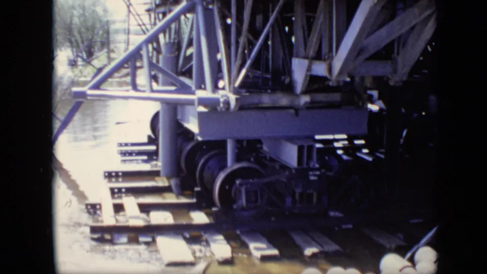 1971 Moscow frame with wheeled machinery, metal supports and river water visible beyond the work surface.