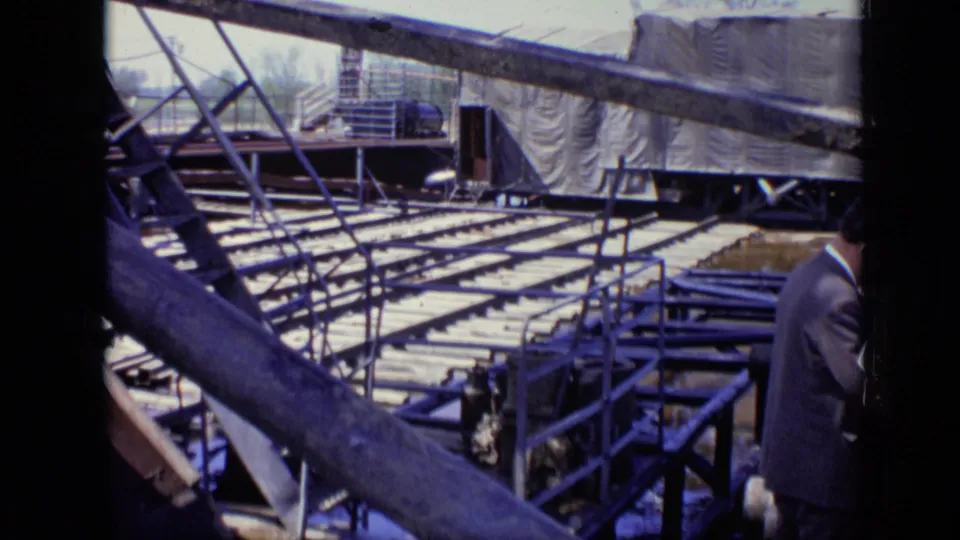 8mm frame of a river worksite in Moscow with scaffolding, metal platforms and a suited adult partly visible at the edge.