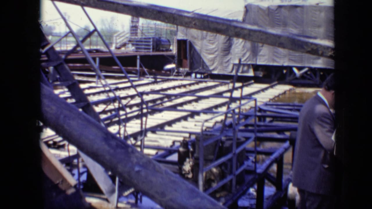 1971 Moscow 8mm frame showing a construction site with metal framing, wooden planks, covered equipment, and a partly visible suited man.