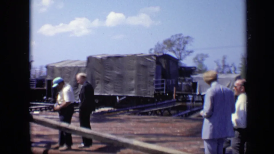 Men in work clothes and jackets pass a covered freight car on rail tracks in this 1971 Moscow industrial-site view.