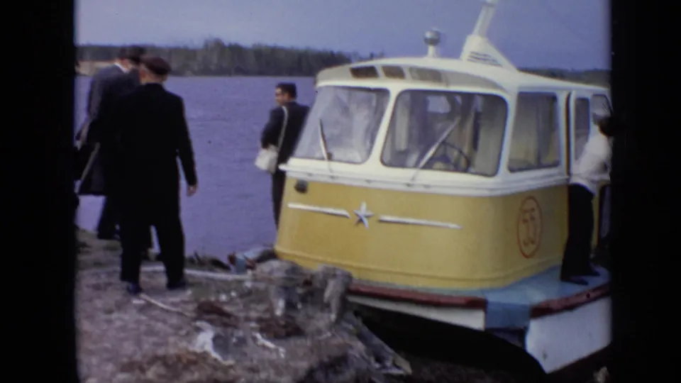 The yellow-and-white amphibious bus is seen close to shore while suited men stand near the water in the 1971 Moscow footage.