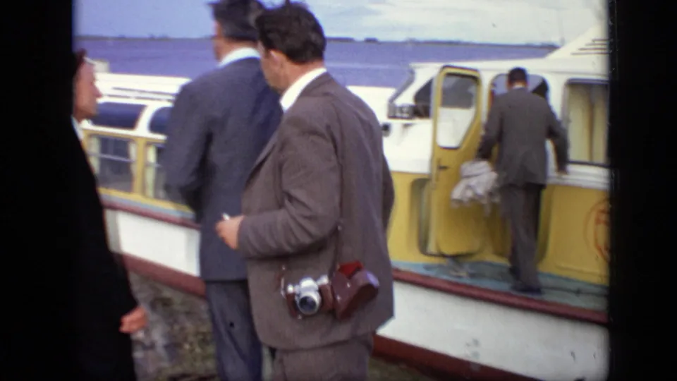 Suited adults continue boarding the yellow passenger boat at the Moscow waterfront, with one man stepping through the open door.