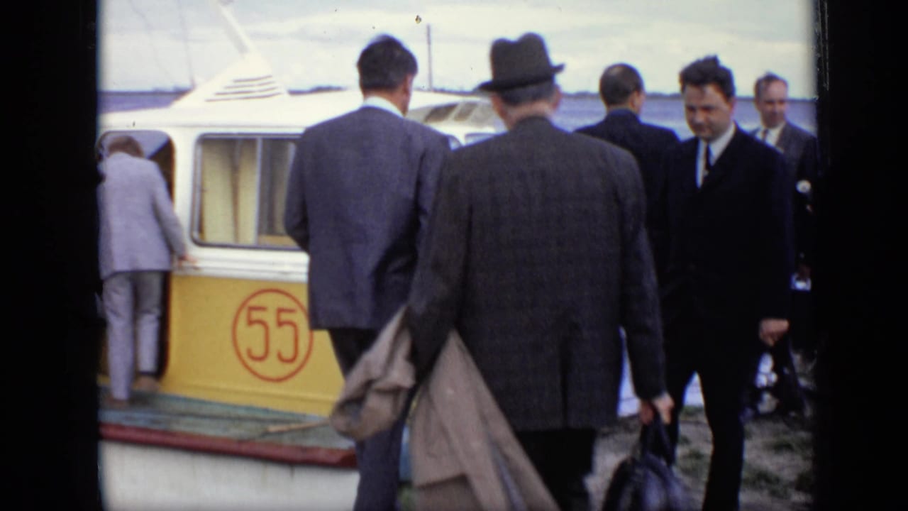 Men in suits and hats board a yellow passenger boat marked with the number 55.