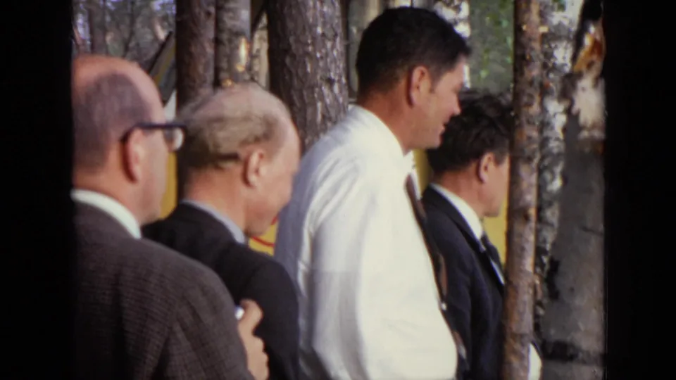 Close 1971 Moscow 8mm view of several men in suits gathered among birch and pine trees during an outdoor inspection.