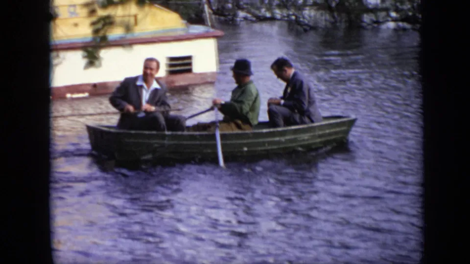 In this 1971 Moscow frame, one man rows while two other adult men sit in a small green boat on a calm river.
