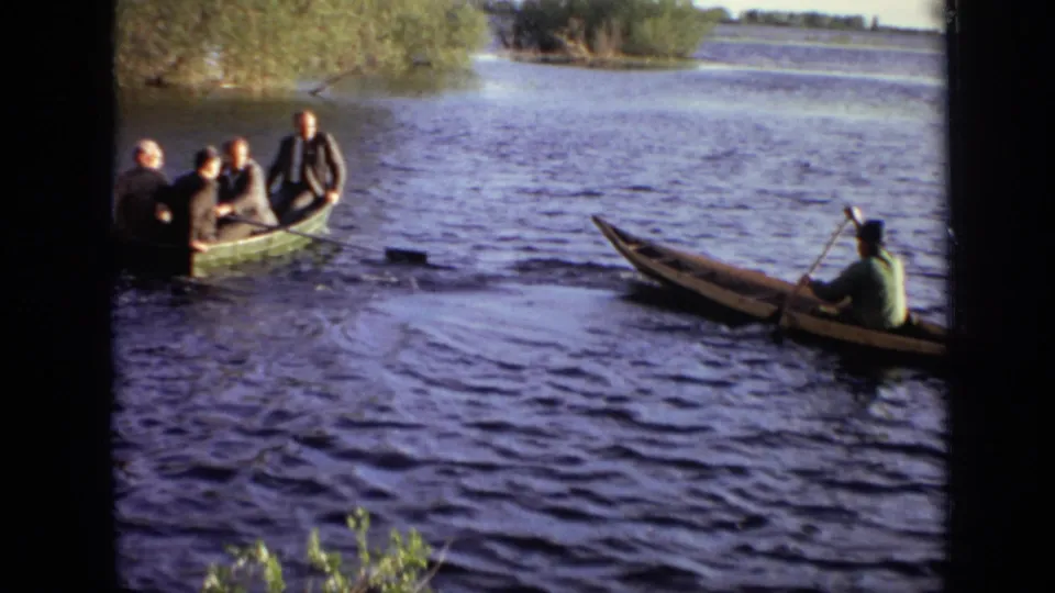Four suited young men in a green rowboat drift away from a pale canoe on a Moscow river in 1971.