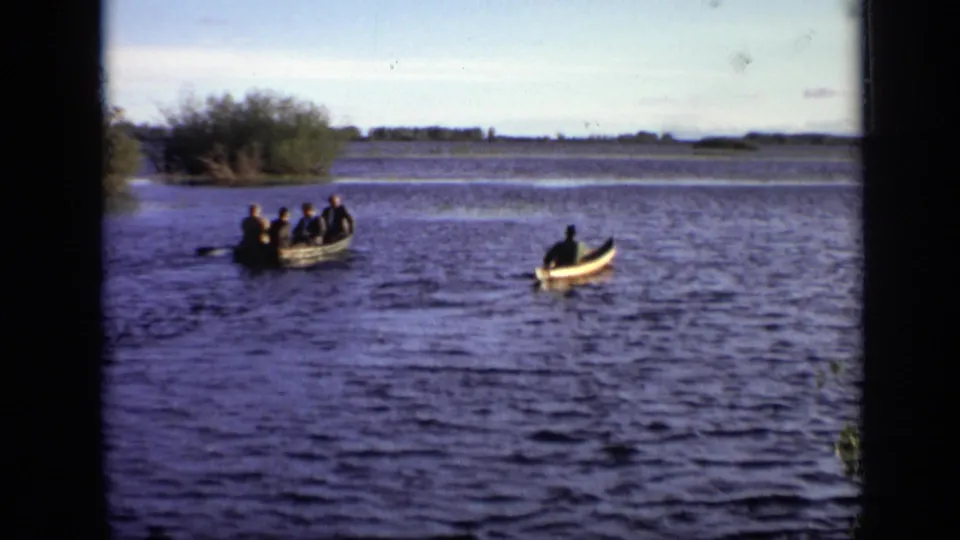 1971 Moscow home-movie view of a group rowboat and separate canoe crossing a broad lake or river.