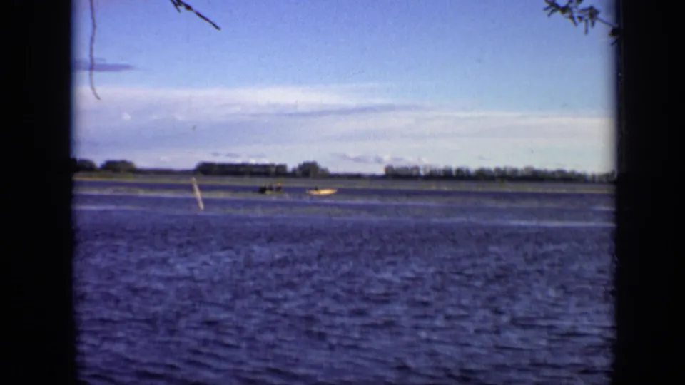 Distant 1971 Moscow lakeside view with small boats barely visible across open water and a low tree-lined horizon.
