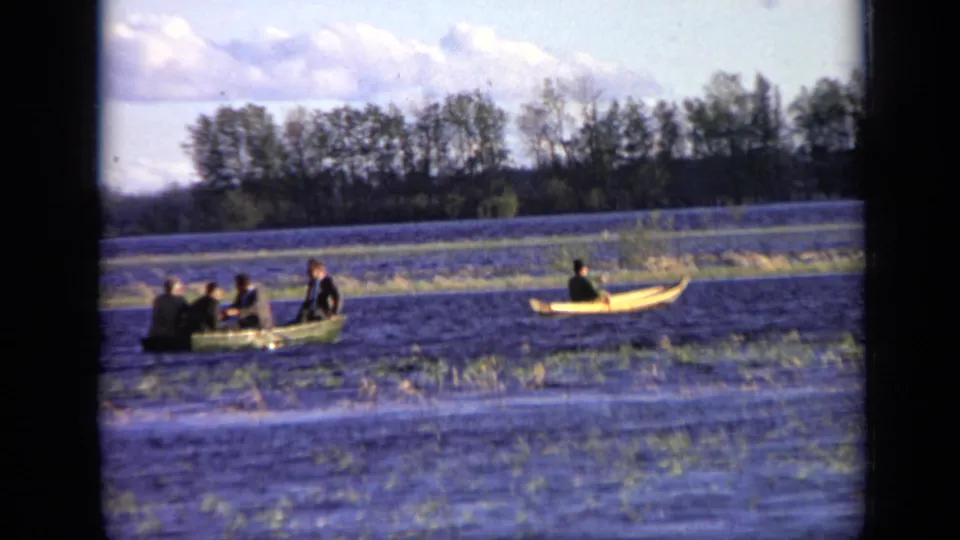 1971 Moscow river scene with a green rowboat carrying several men and a separate yellow canoe moving across calm water.