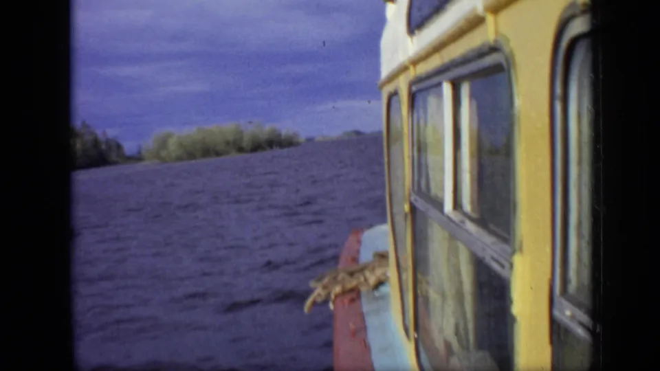 Moscow 1971 8mm frame with the side of a cabin boat crossing choppy water under a cloudy sky.