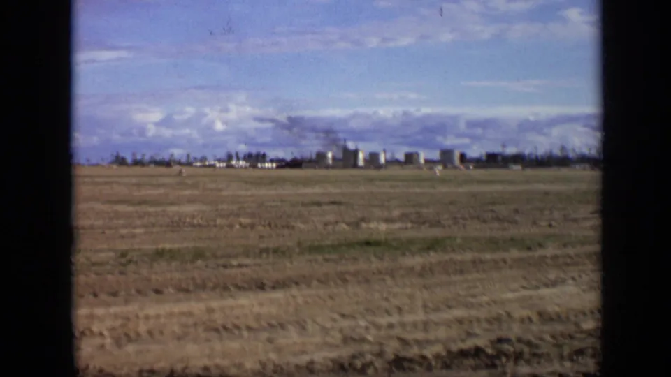 1971 Moscow 8mm wide frame showing open land, distant structures, and a broad partly cloudy sky.