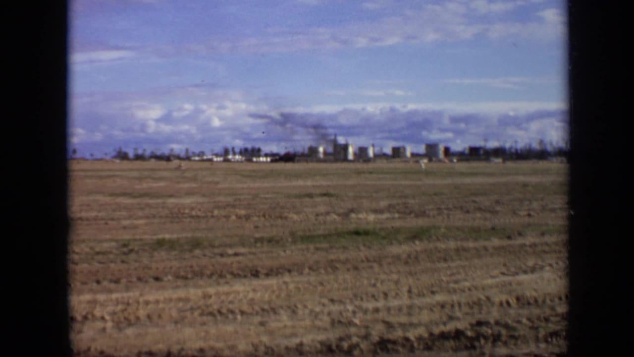 1971 8mm Moscow-area view across a barren plain toward a distant industrial complex with smoke rising from stacks.