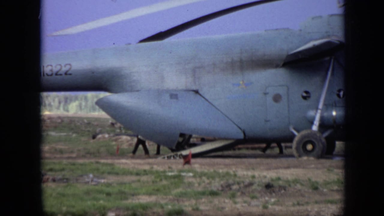 Gray helicopter fuselage with partial CCCP marking parked or landing in a grassy field.
