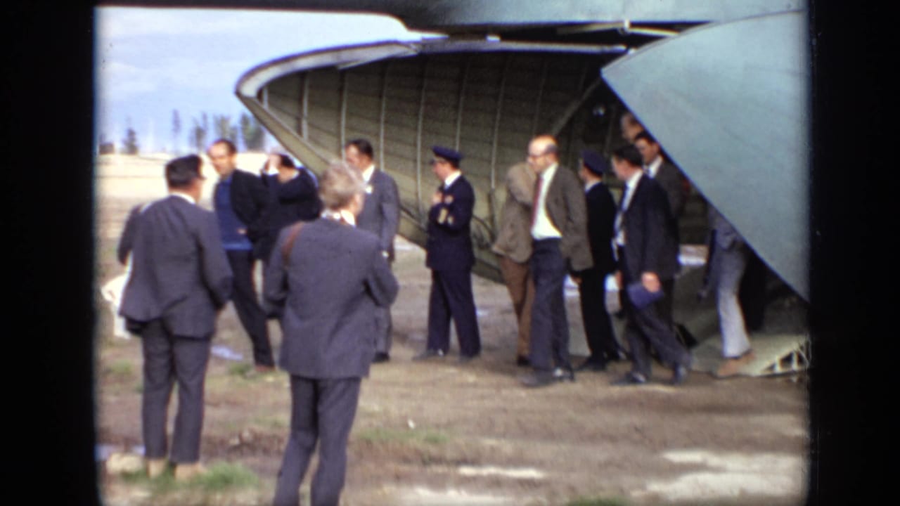 1971 Moscow airfield scene with civilian and uniformed figures standing near the rear hatch of a Soviet aircraft.