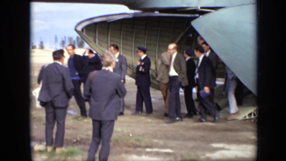 1971 Moscow airfield scene with civilian and uniformed figures standing near the rear hatch of a Soviet aircraft.