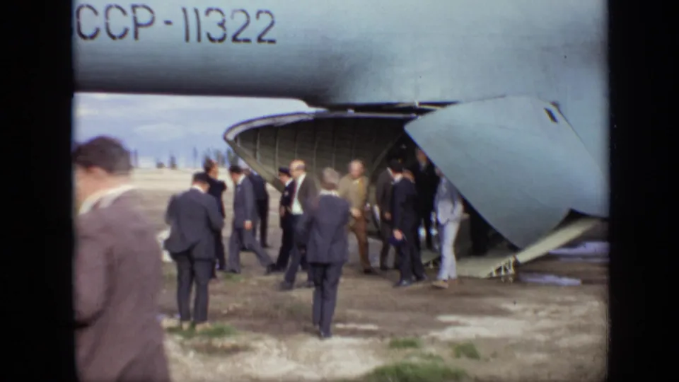 A handheld 8mm view shows officials near the rear ramp of Soviet aircraft CCCP-11322 at a Moscow airfield in 1971.