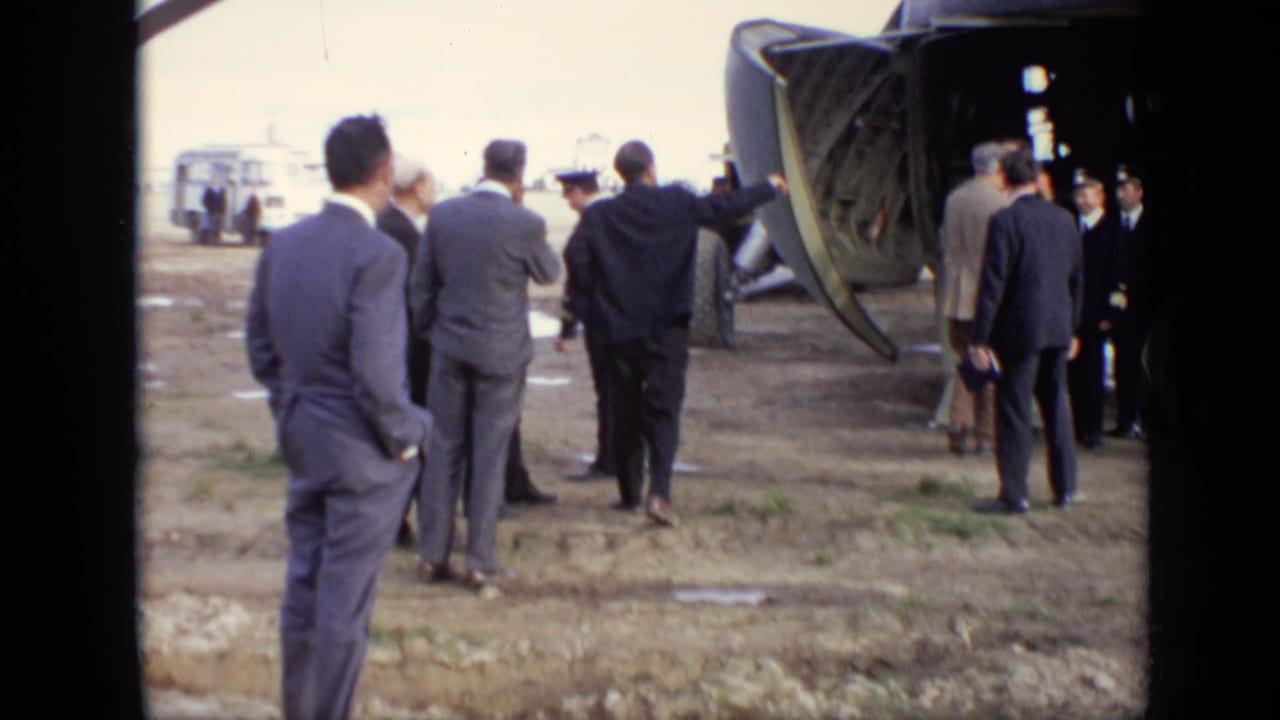 Several adult men in suits stand near uniformed personnel by the open rear ramp of a transport aircraft in 1971 Moscow footage.