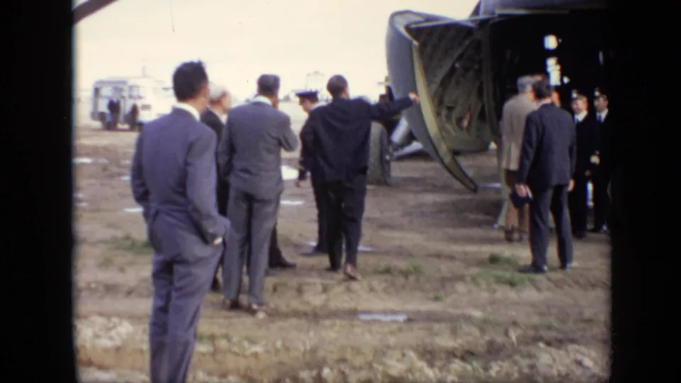 Several adult men in suits stand near uniformed personnel by the open rear ramp of a transport aircraft in 1971 Moscow footage.