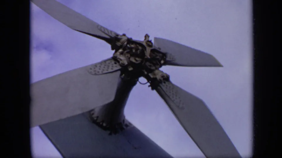 The 8mm footage holds on the aircraft propeller assembly, with blades crossing a pale blue sky.