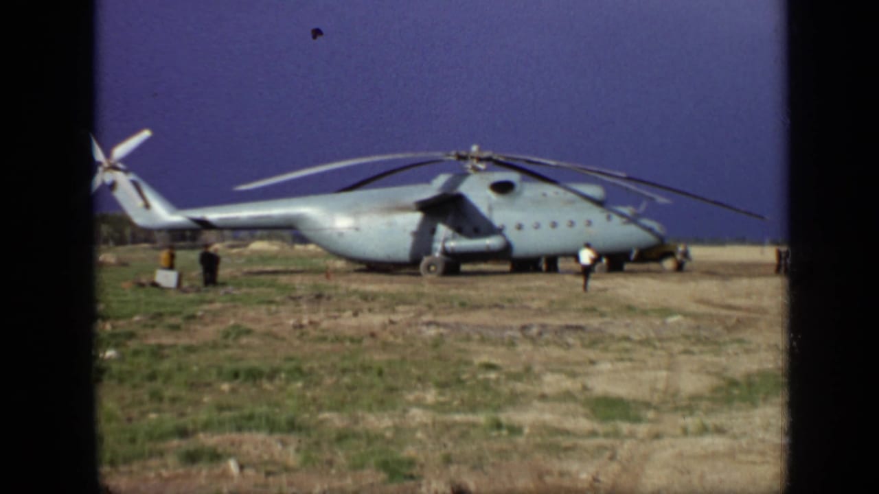 Side view of the large helicopter in Moscow, 1971, with distant figures near the aircraft and its rotors at rest.