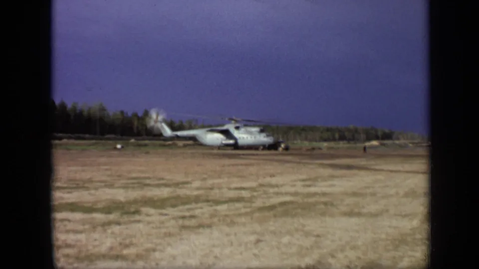 1971 8mm frame near Moscow with a large helicopter viewed across dry grass, its rotors blurred against the sky.