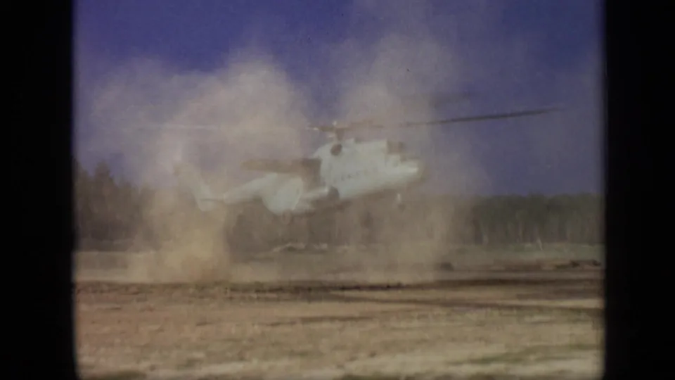 1971 Moscow 8mm frame showing the helicopter partially hidden as dust churns upward across the open field.