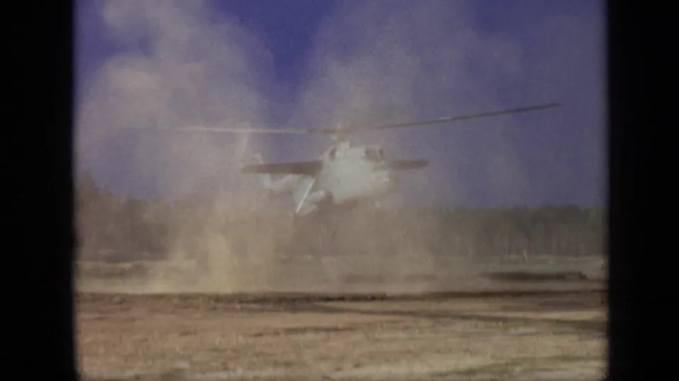 1971 Moscow 8mm frame of the helicopter receding or rising behind a heavy dust cloud over the dirt field.