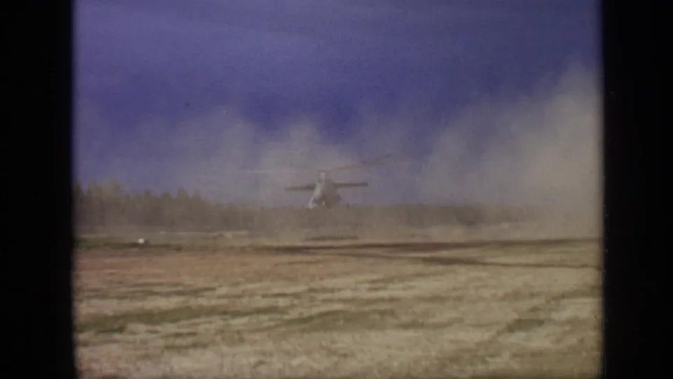 The helicopter appears farther back over the field as dust drifts across the 1971 Moscow 8mm frame.