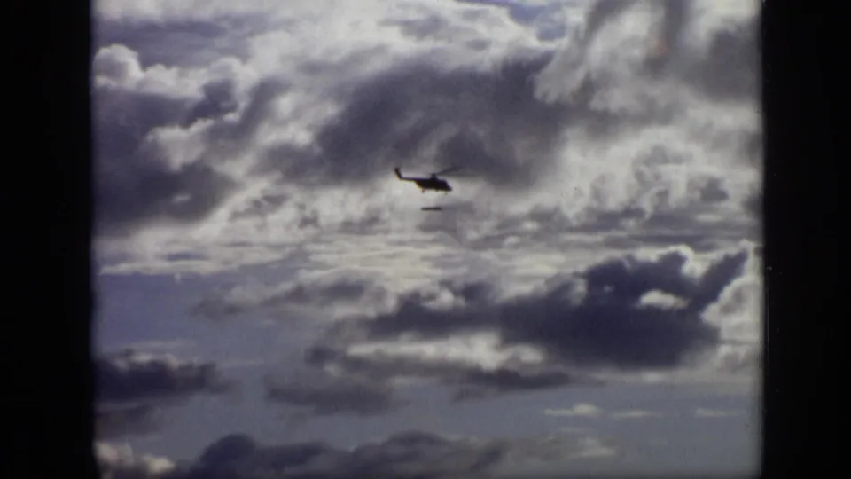 1971 Moscow home-movie frame showing a small helicopter silhouetted against dense overcast clouds.