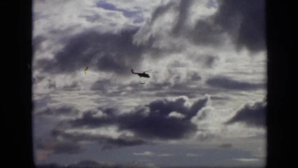 1971 Moscow 8mm frame with a helicopter moving through a dramatic cloud-filled sky.