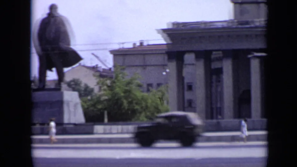 1971 Moscow street view with a statue on a plinth, large columned building, pedestrians, and a passing car.