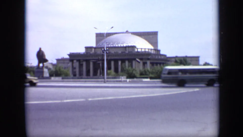 1971 Moscow street scene with a domed columned building, statue, streetlight, and bus crossing the frame.