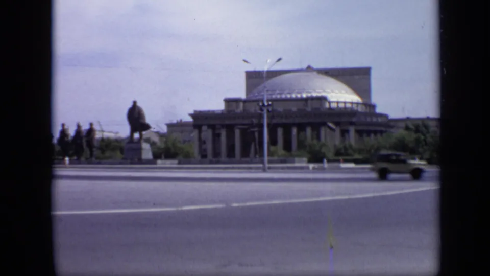 1971 Moscow view with pedestrians near a statue, a domed public building, streetlight, and car on a wide road.