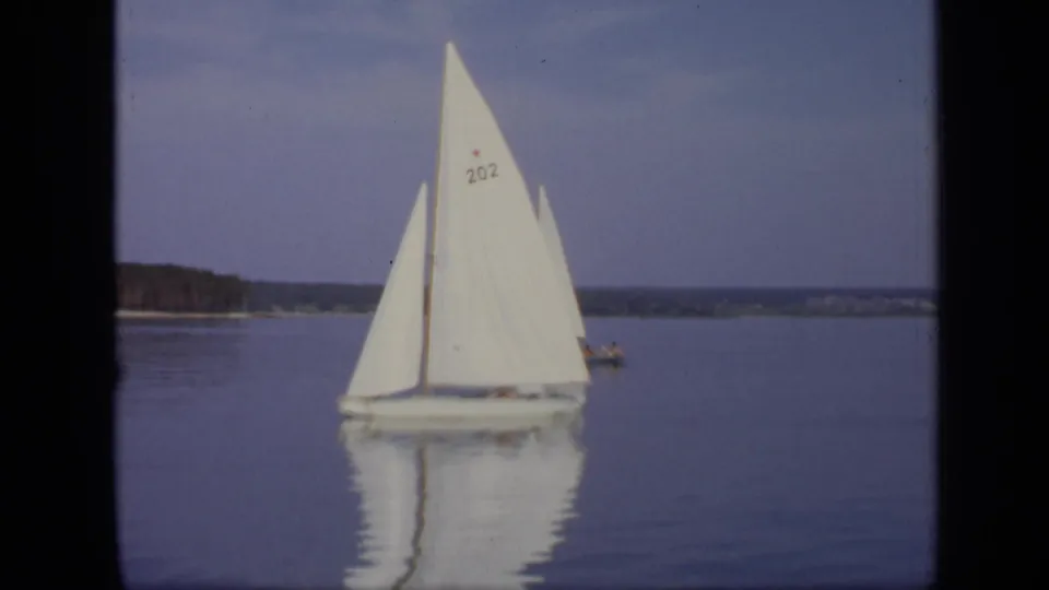 A white sailboat marked 202 passes on calm water in supported 1971 Moscow lake footage.