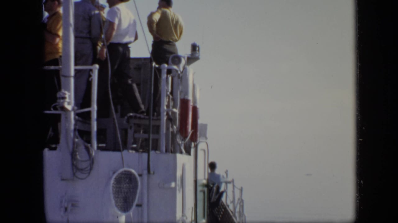 Upper boat deck passengers in casual clothing stand by railings in the supplied 1971 Moscow home-movie footage.