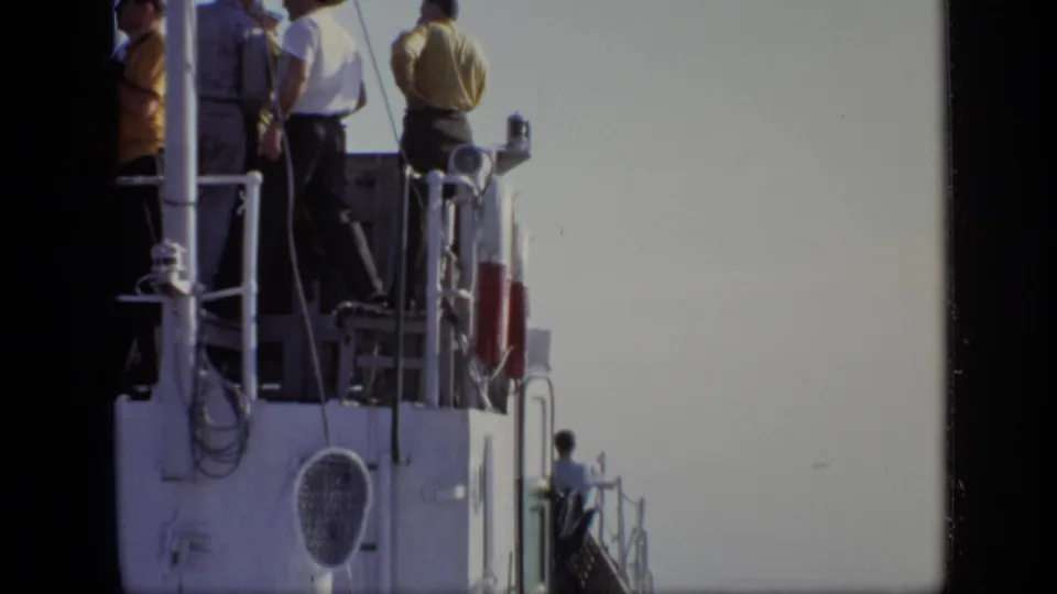 Upper boat deck passengers in casual clothing stand by railings in the supplied 1971 Moscow home-movie footage.