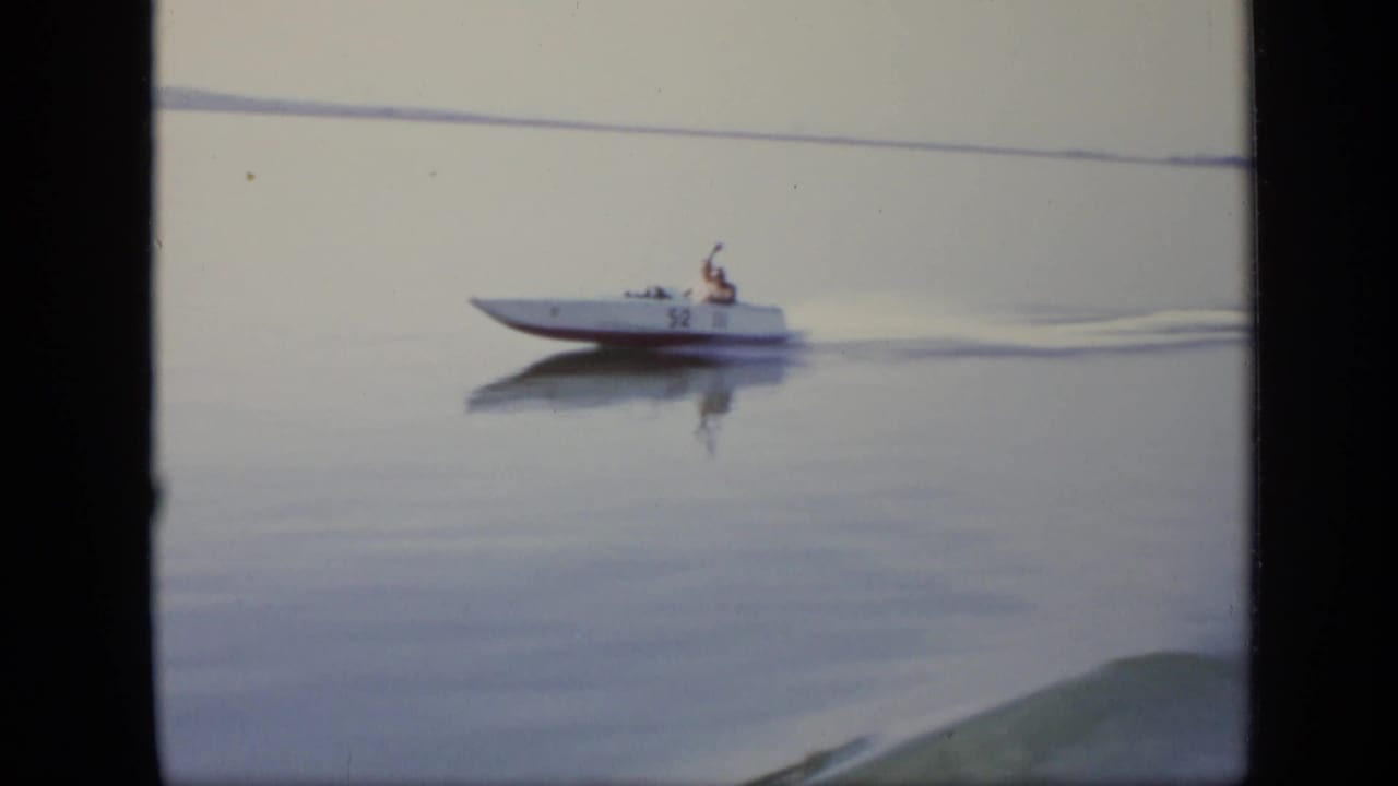 A white speedboat marked 52 travels across a calm Moscow river surface in the 1971 8mm footage.