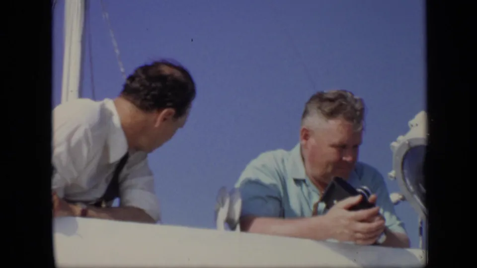 A later frame shows two adult men on the boat, including one in a light blue shirt looking down at a camera.