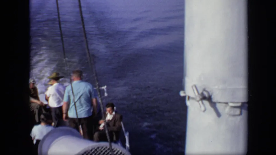 1971 8mm home-movie frame showing passengers on a boat in Moscow, Russia, with wake trailing across open water.