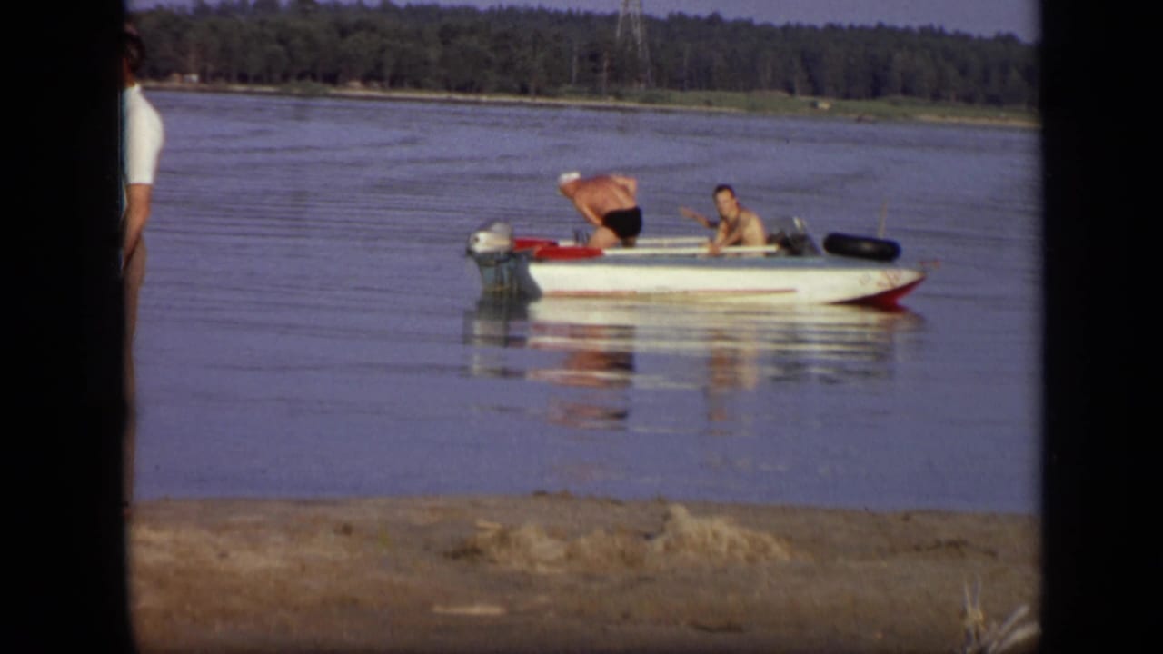 1971 Moscow frame with two men in a small motorboat while a partial standing figure appears near the foreground edge.