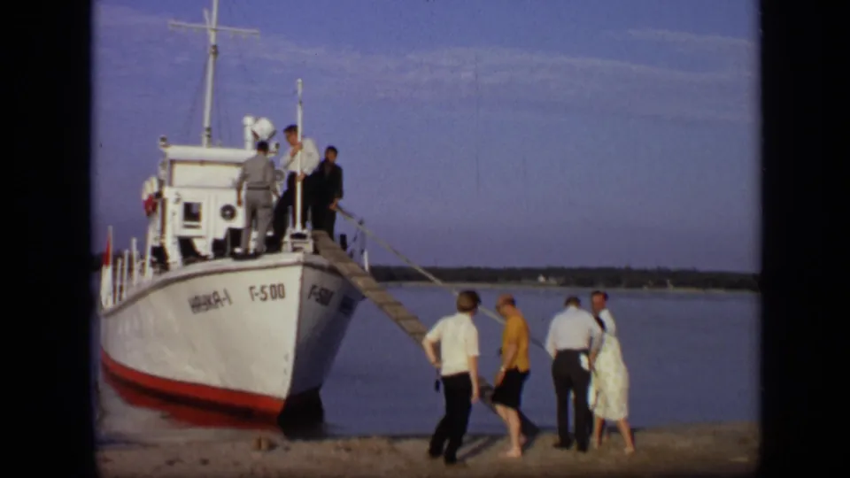 1971 Moscow waterfront frame showing a small group beside a wooden ramp leading to a marked white and red passenger boat.