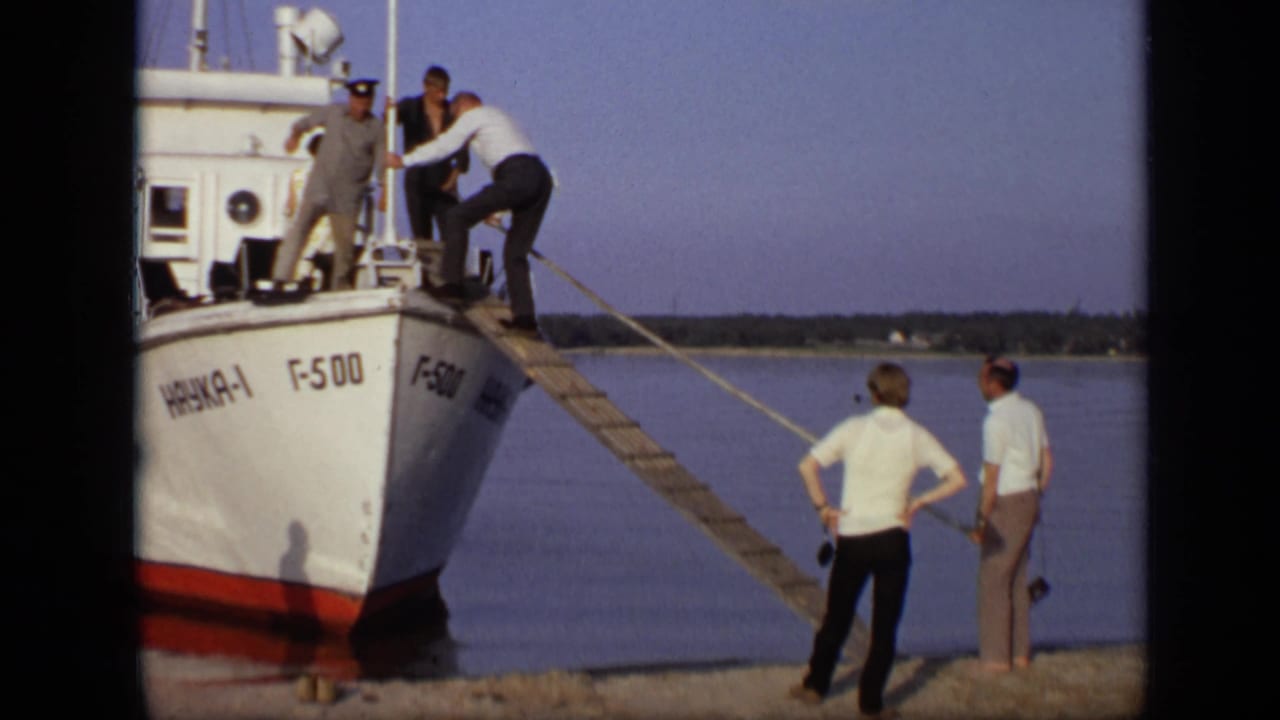 A man in a white shirt climbs the gangplank while people stand on the boat and shore.