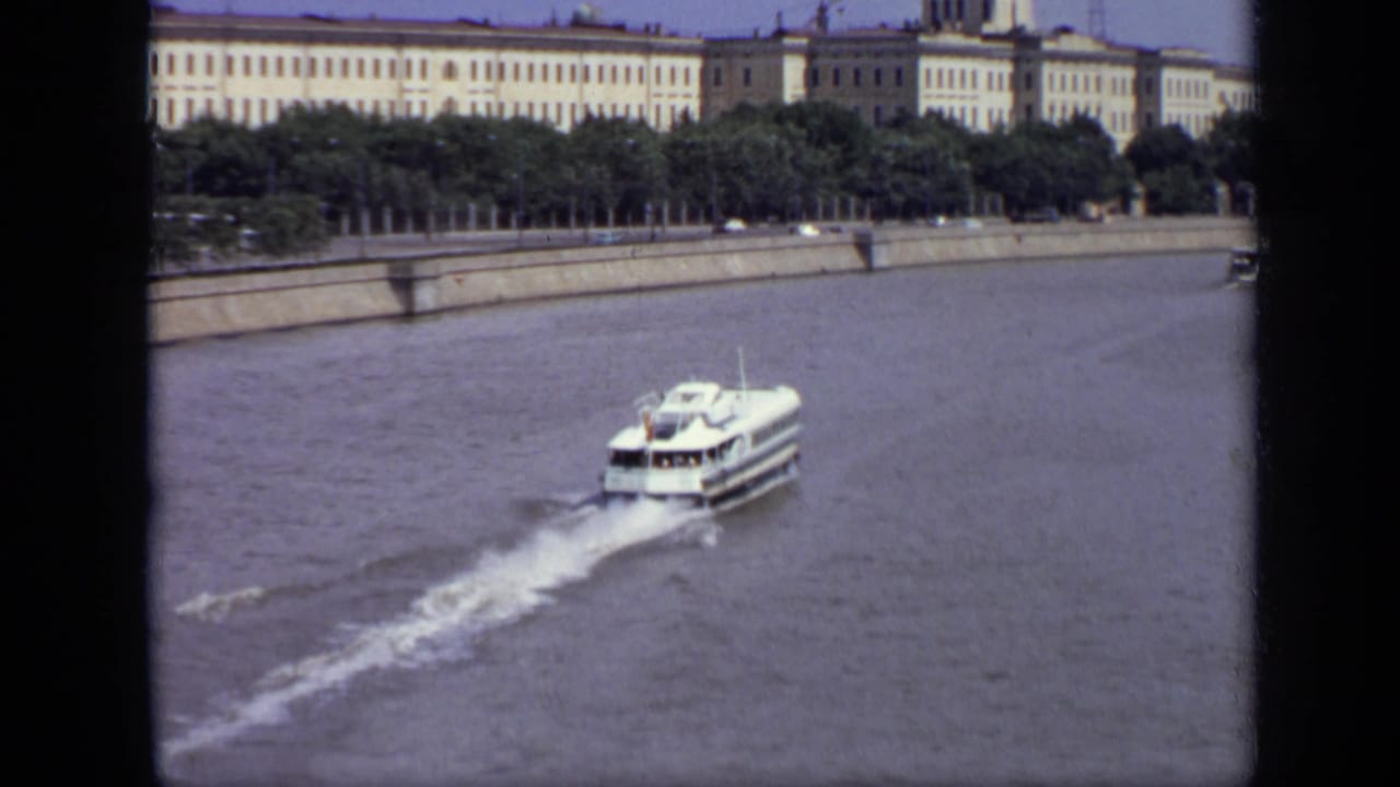 White passenger ferry crossing the Moscow riverfront in 1971, with trees and monumental buildings behind it.