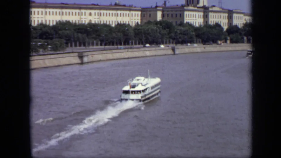 White passenger ferry crossing the Moscow riverfront in 1971, with trees and monumental buildings behind it.