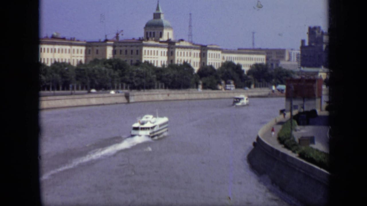 Moscow riverfront with a white boat passing near a large domed building.